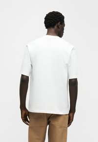 Λευκό βαμβακερό μπλουζάκι με κοντά μανίκια, άνετη εφαρμογή και στρογγυλή λαιμόκοψη. Ομαλή υφή, χωρίς ορατά σχέδια ή διακοσμητικά στοιχεία.