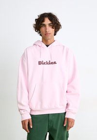 Felpa con cappuccio rosa e tasca frontale. Presenta un logo in testo marrone. Realizzata in tessuto morbido con una vestibilità comoda e polsini a coste.
