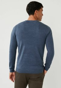 Blauer Strickpullover mit langen Ärmeln, Rundhalsausschnitt und geripptem Saum. Glatte Textur, taillierte Passform und Rückansicht gezeigt.