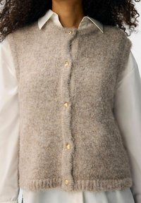 Beige Wollmischung-Weste mit weicher Textur, rundem Halsausschnitt und goldenen Knopf-Verschlüssen. Hat einen geraden Schnitt und gerippten Saum.