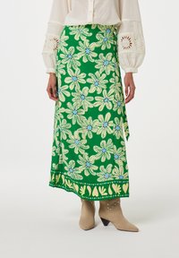 Groene maxi rok met bloemenpatroon, voorzien van een levendig plantenmotief met gele accenten en een decoratieve zoom, gemaakt van lichtgewicht stof.