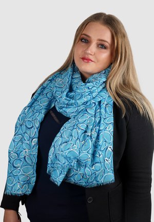 Lichtblauwe sjaal met een cirkelpatroon in donkerblauw en zilveren accenten. Gemaakt van zachte stof met franjen aan de randen.