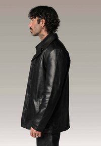 Veste en cuir noir avec col en V, fermeture à boutons et poches latérales. Texture lisse avec une silhouette décontractée et une coupe ajustée.