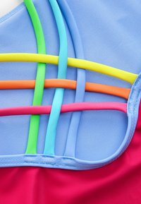Multifarvet atletisk top med blå bund. Har smalle elastiske stropper i grøn, gul, orange, pink og lyseblå i et krydsmønster.