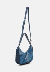 Dżinsowa torba na ramię z plecionym niebieskim skórzanym paskiem, z patchworkowym wzorem z różnych niebieskich kawałków dżinsu i zamknięciem na zamek.