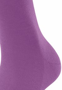 Gros plan sur un tissu tricoté violet au niveau du talon d'une chaussette, montrant les détails de texture et de couture.