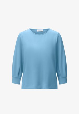 Világoskék, hosszú ujjú blúz kerek nyakkal és mandzsettás ujjal, fehér háttéren bemutatva.