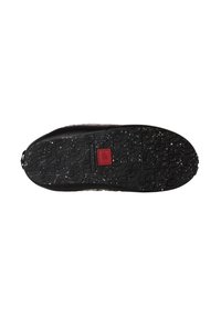 Suola di scarpa nera con un motivo texture, macchie bianche e una toppa rossa quadrata al centro.