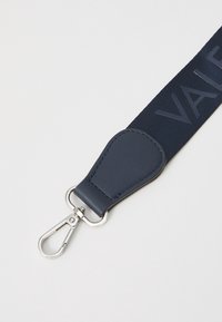 Marinblå rem med texturerad tygdesign, förhöjd med en slät läderdel och ett silverfärgat metallklämma för fästning.