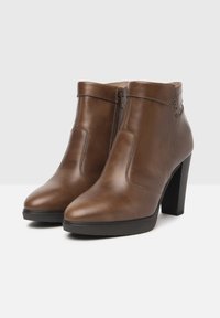 Brown leather ankle boots with a pointed toe, side zippers, and a chunky heel. Smooth texture with subtle stitching accents.