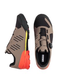 Scarpe sportive marroni e nere con una superficie texturizzata, intersuola gialla e suola rossa con un motivo esagonale. Il sistema di chiusura include un sistema a pulsante.