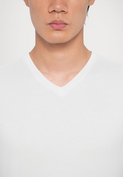 Tricou alb cu decolteu în V, realizat dintr-un material moale, având o textură netedă și o croială clasică. Fără modele sau logo-uri vizibile.