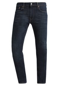 Vaqueros de mezclilla azul oscuro con un ajuste ceñido, diseño clásico de cinco bolsillos, bragueta con botones y detalles de costura sutiles. Textura suave y sin patrones.