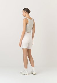 Szary krótki top w połączeniu z białymi szortami rowerowymi. Strój charakteryzuje się prostym wzornictwem oraz miękką, gładką tkaniną, z delikatnymi fakturami.
