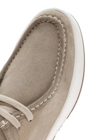 Scarpa in suede beige con superficie texturizzata, suola in gomma bianca a contrasto e dettagli cuciti lungo il bordo. Presenta lacci dello stesso colore.