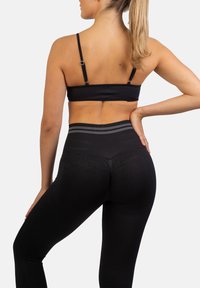 Zwarte geribbelde sportbra en hoge taille legging met een grijze gestreepte tailleband, met een getailleerd ontwerp en een soepele textuur.