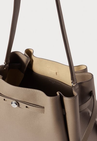 Ruskea nahkaolkalaukku, jossa on teksturoitu pinta, avoin pää ja lyhyet olkahihnat. Vuori vaaleanbeigea mokkanahkaa.