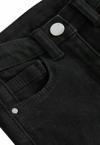 Jeans de denim negro con un bolsillo frontal, cierre de botón metálico y costuras en contraste. Primer plano que muestra la textura y las costuras detalladas.