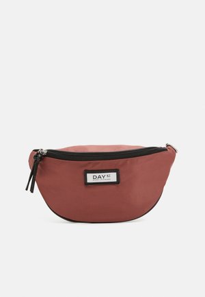 Petit sac banane en tissu couleur rouille avec fermeture éclair noire et écusson rectangulaire blanc portant le logo "DAY ET" sur un fond uni.