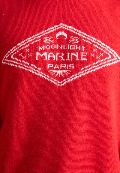 Röd stickad tröja med en vit diamantformad logotyp med texten "MOONLIGHT MARINE PARIS" och dekorativa accenter. Slät textur.