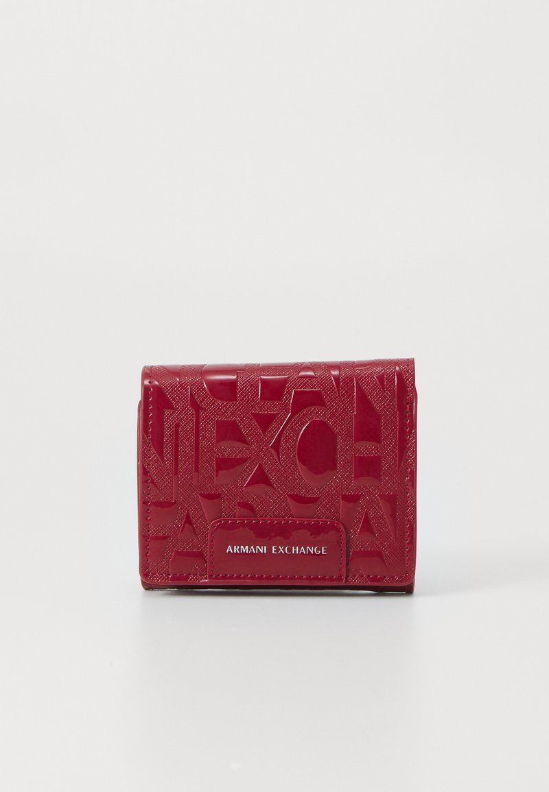 Compact red wallet embossed with overlapping letters and a front patch labeled "Armani Exchange," placed on a white surface.