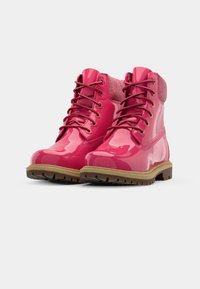 Botas de tornozelo de couro laqueado rosa com detalhes em tecido texturizado rosa, bico redondo, sola de borracha e sola exterior marrão com cravos.