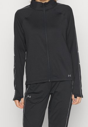 Person wearing black zip-up jacket and matching pants with grey Under Armour logos and visible stitching details.