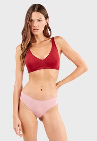 Sujetador rojo con diseño de escote en V, tirantes anchos y acabado sin costuras. Braguitas rosas con una textura suave y cinturilla con ondas.