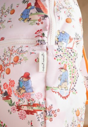 Rosafarbener Stoff mit floralen Mustern und Illustrationen von Paddington Bär, mit einem weißen Reißverschluss und einem Etikett an der Seite zur Produktidentifikation.