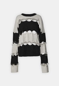 Pull en maille noir et gris clair avec découpes circulaires et anneaux en métal. Coupe décontractée et poignets côtelés. Surface texturée.