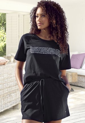 Black short-sleeve tee and shorts set in soft fabric, featuring a relaxed fit and drawstring waist, with white text accents on the shirt.