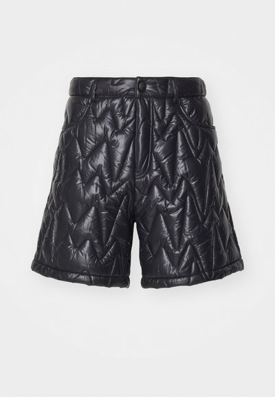 Schwarze gesteppte Shorts aus glänzendem, gepolstertem Stoff. Mit Reißverschluss, Fronttaschen und einem Zickzack-Stichmuster auf der Oberfläche.