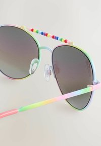 Sateet värvides aviator stiilis prillid gradient-punaste raamidega ja värviliste helmesakentitega, tumedate läätsede ja selgete nina padjanditega.