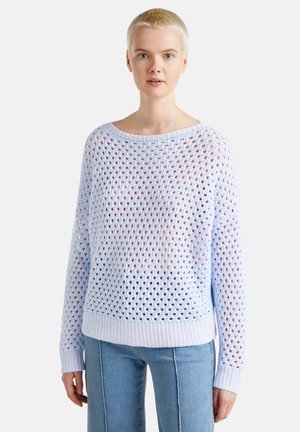 Pull en tricot bleu clair avec un motif ajouré, décolleté large et poignets côtelés. Associé à un pantalon en denim clair.