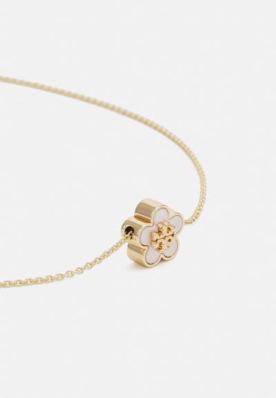 Goldkette mit einem blumenförmigen Anhänger, der mit einer weißen Emaille-Oberfläche und einem erhabenen Zentrumsdetail verziert ist.