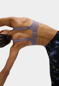 Lila sportbh met verstelbare bandjes, een gladde textuur en een racerback ontwerp, gecombineerd met patroon zwarte leggings.