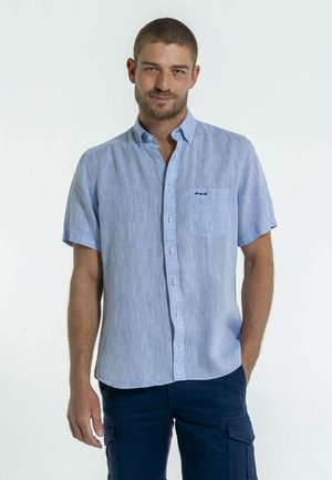 Chemise à manches courtes en tissu bleu clair avec une finition texturée, dotée d'un col boutonné et d'une poche poitrine avec broderie.