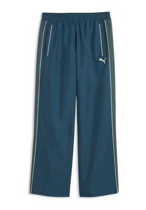 Granatowe spodnie sportowe z elastycznym pasem, bocznymi kieszeniami, białym obszyciem wzdłuż nóg oraz małym białym logo Puma na prawej udzie.
