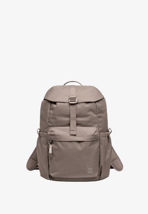 Beige fabric backpack with a rounded top, adjustable straps, front zip pocket, side pockets, and a logo on the bottom right.