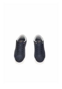 Sneakers in tela blu navy con suole e lacci in gomma bianca. Logo dorato "GAP" sulla linguetta. Texture liscia e design a punta tondeggiante.