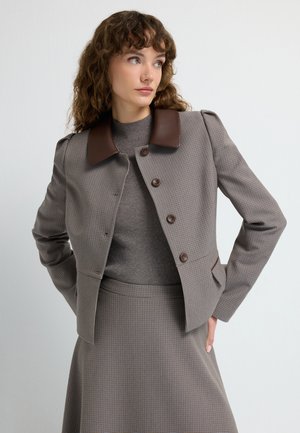 Brunternet jakke med en brun faux læder krave, knaplukning og struktureret silhuet, parret med et matchende nederdel.