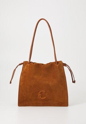 Bruine suede tote bag met slanke leren schouderbanden en trekkoordzijden, met een subtiel reliëflogo in het midden van de voorkant.