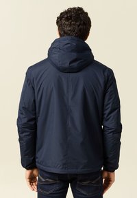 Giacca imbottita blu navy con cappuccio, polsini elasticizzati e una texture liscia. Presenta un design semplice e un taglio dritto. Vista posteriore.