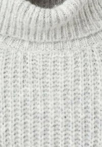 Maglione grigio chiaro a maglia con colletto alto, caratterizzato da una texture a coste e fibre visibili, che enfatizzano il suo aspetto morbido e accogliente.