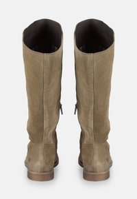 Une paire de bottes hautes en suède marron avec des zips latéraux et des talons bas, vues de l'arrière sur un fond blanc uni.