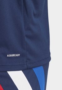 Námořnická modrá sportovní látka s bílým textem "AEROREADY" nad diagonálními červenými, bílými a modrými pruhy na spodní části.