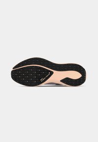 Talpa neagră cu un model texturat pentru aderență, brâu de culoare bej deschis și logo-ul Nike. Trecere lină de la o culoare închisă la una deschisă pe marginile încălțămintei.