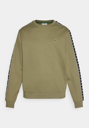 Sudadera verde oliva con cuello redondo, que presenta paneles laterales negros decorados con texto de logotipo blanco y un pequeño logotipo de cocodrilo bordado.