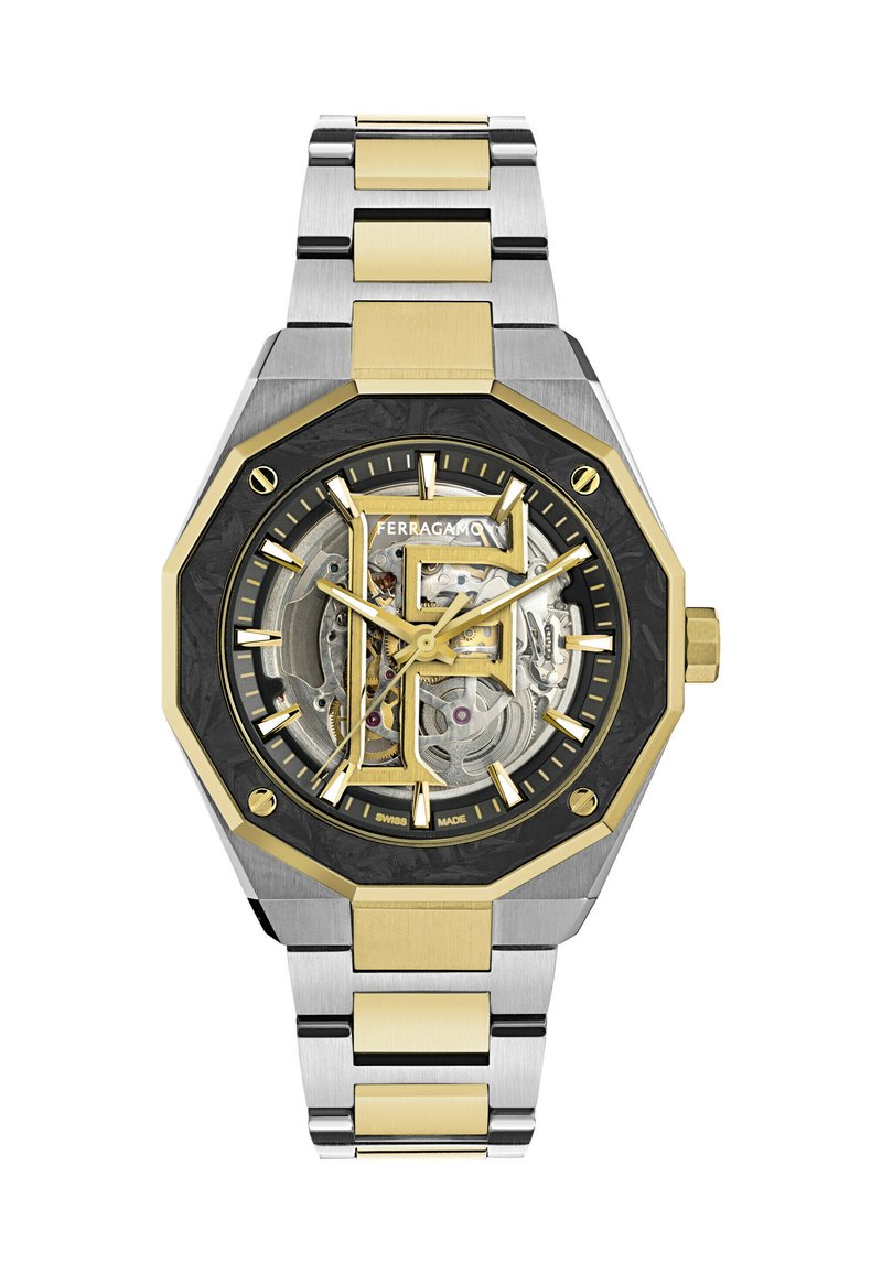 Ceas de mână din metal cu două tonuri, cu lănțișoare aurii și argintii, bezel octagonal negru și auriu și cadran skeleton care arată mecanismele interioare și logo-ul "Ferragamo".