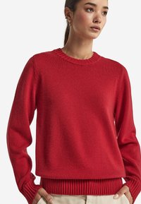 Roter Strickpullover mit runder Halskante, gerippten Bündchen und Saum. Glatte Textur mit lockerem Schnitt, geeignet für legere Outfits.